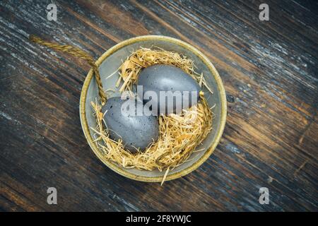 Small gray bowl with gray Easter eggs on rustic colorful wood, Easter decoration, top view with copy space Stock Photo