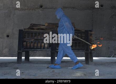 Mumbai, India. 15th Apr, 2021. A municipal worker wearing a personal protective equipment suite (PPE) cremates a body of a person who died due to coronavirus disease in Mumbai.Amidst the rising in coronavirus cases in Maharashtra, there is a 15 days of curfew starting from 14th April till 30th April, only essential service will be allowed. (Photo by Ashish Vaishnav/SOPA Images/Sipa USA) Credit: Sipa USA/Alamy Live News Stock Photo