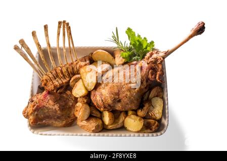 Roasted leg and chops of lamb in ceramic tray with potatoes and parsley, isolated on white, top view Stock Photo