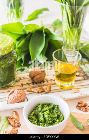 Homemade wild garlic pesto in a white bowl and its ingredients on a tray on white background Stock Photo