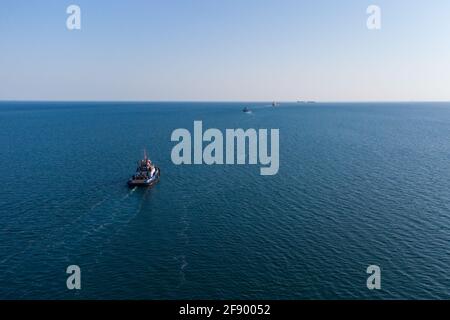 The sea tug moves from the port water area towards the open sea. Photo from the helicopter. View from above Stock Photo