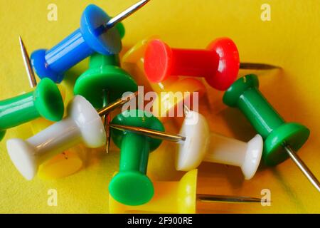 close up of colorful thumbtacks in the colors red yellow white blue green on yellow paper Stock Photo