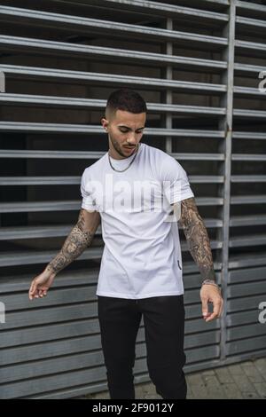 Vertical shot of a young European man with tattooed arms Stock Photo