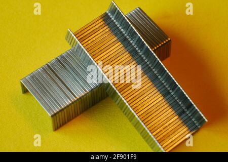 close up of metal staples on yellow paper Stock Photo