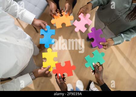 African American People Hands Holding Colorful Puzzle Stock Photo
