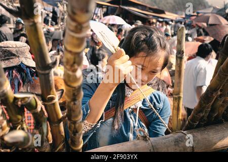 Bac Ha, Vietnam - April 4, 2016: Young Hmong tribe girl make traditional crafts at Can Cau Saturday market in Vietnam Stock Photo