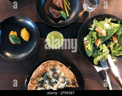 Overhead view of vegetarian pizza, chicken broccoli salad, steak with asparagus, sorbet and a glass of fresh celery juice Stock Photo