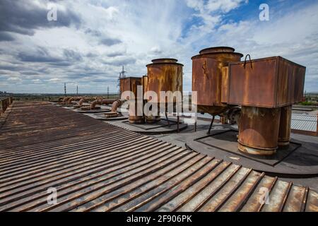 On the roof of heat electric plant. Old rusted pipes of ventilation system. Blue sky with clouds. Karaganda, Kazakhstan. Stock Photo