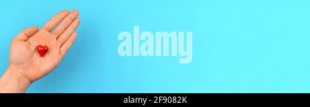 Man gives a red heart in a hand, helping hand and charity concept banner background, copy space photo Stock Photo
