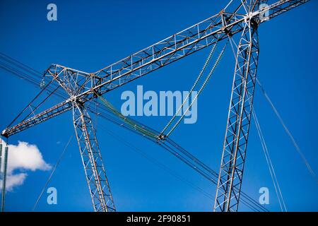 Electric tower (pole) on blue sky background. Glass insulators (isolators). Close-up photo. Blue sky with cloud. Stock Photo