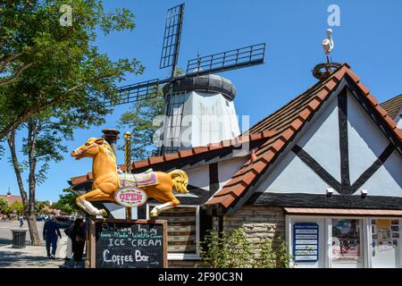 A solo Carousel horse used for  advertising the Ice cream shop in front of a windmill in half timbered  Danish Village in Solvang, CA Stock Photo
