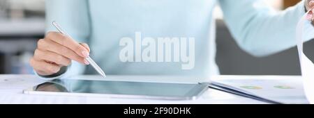 Woman holding stylus with her hand over a tablet and turning page in documents closeup Stock Photo