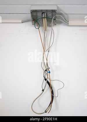 junction box of an open electrical system with dangling wires, white wall background Stock Photo