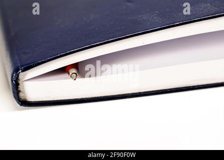 Red ballpoint pen on the blank white pages of a closed notebook. Inspiration and storytelling. Stock Photo