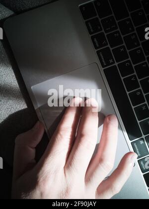 Man's hand on the laptop keyboard touchpad. Top view. Stock Photo