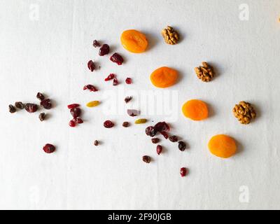 Walnuts, raisins, dried cranberries and dried apricots on white table Stock Photo