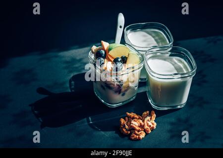 three yoghurts on a black background with walnuts. breakfast Stock Photo
