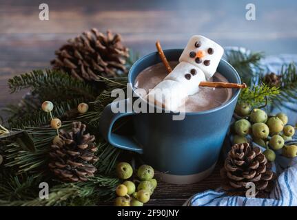 Marshmallow snowman in a mug of hot chocolate with winter decor. Stock Photo