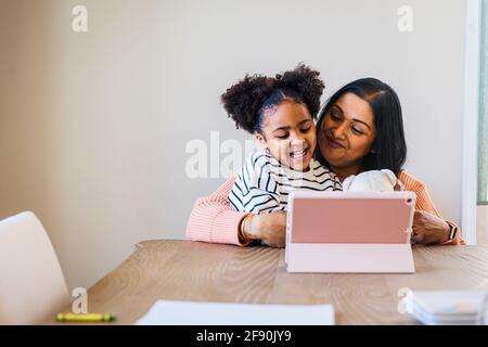 Smiling granddaughter and grandmother using digital tablet at home Stock Photo