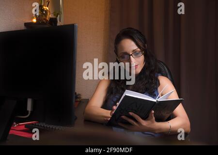 pretty middle aged latin woman reading in her work area Stock Photo