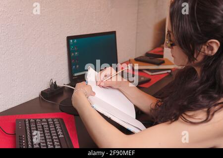 pretty middle-aged latin woman writing in her workspace Stock Photo