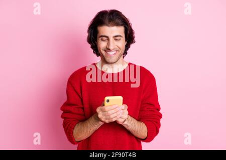 Portrait of nice cheerful focused guy using gadget app writing media post isolated over pink color background Stock Photo