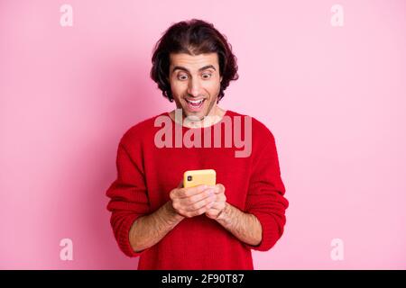 Portrait of nice cheerful focused amazed lucky guy using app browsing media post isolated over pink color background Stock Photo