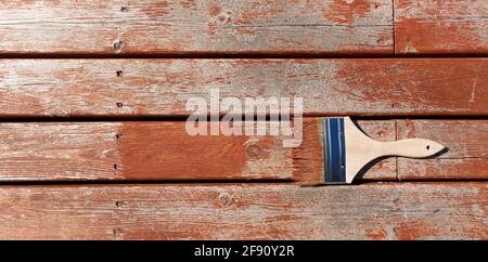 Brush loaded with stain on outdoor wooden cedar for resurfacing the home deck in flat lay format Stock Photo