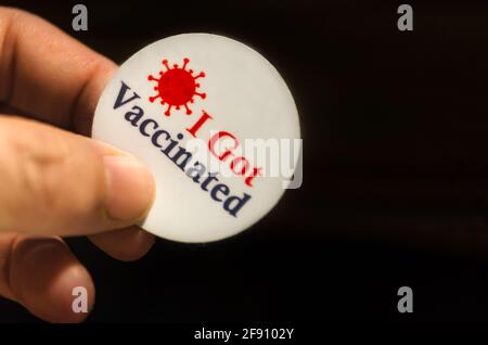 A patient holds an “I Got Vaccinated” sticker and COVID-19 vaccination card after receiving the COVID-19 vaccine by Pfizer-BioNTech in Mobile, Alabama. Stock Photo