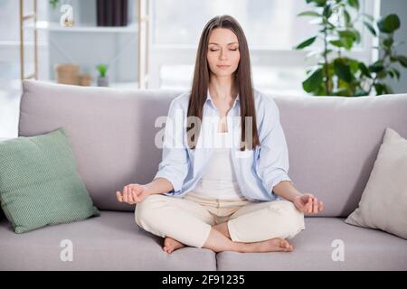 Full size photo of nice optimistic brunette long hairdo lady sit on coach wear blue shirt at home Stock Photo