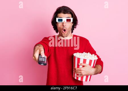 Photo portrait of amazed man with popcorn watching blockbuster using console wearing 3d glasses isolated on pastel pink color background Stock Photo