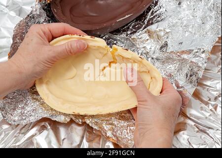Easter Egg - Close-up of hands breaking homemade stuffed chocolate egg. Top view. Horizontal shot. Stock Photo