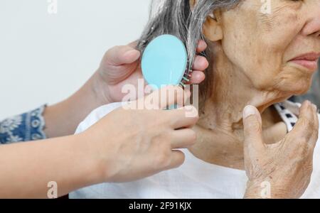 elderly woman combing hair by caregiver Stock Photo