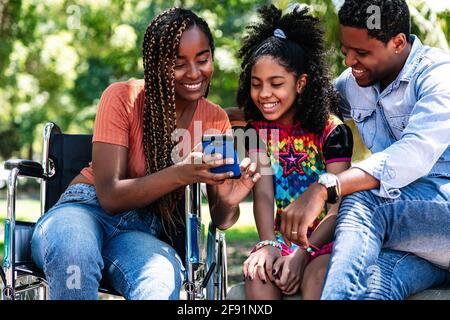 Woman in a wheelchair at the park with family. Stock Photo