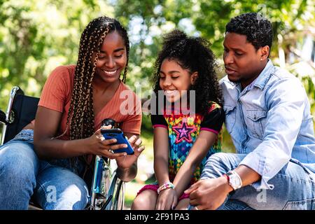 Woman in a wheelchair at the park with family. Stock Photo