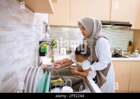 muslim mother wash her son hand in the kitchen sink Stock Photo
