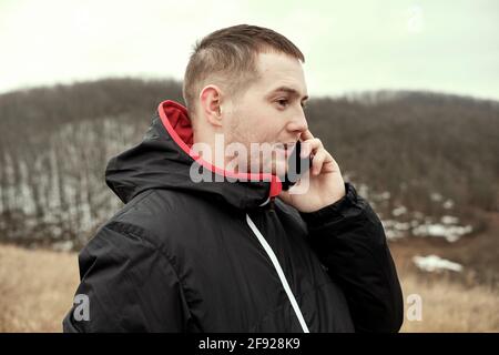the guy is talking on the phone near the forest. Communication quality outdoors. Call rescuers by phone. Lost in the woods. Stock Photo