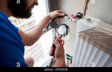 Close up of plumber filling pipes with pressurized air to inspect for leaks in new installation, using air compressor while checking gas tightness of heating system. Concept of home renovation Stock Photo