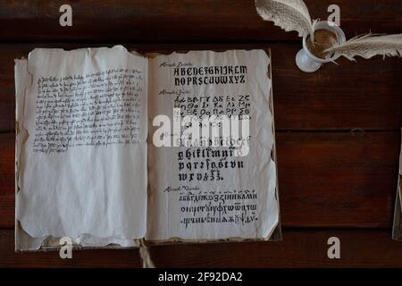 An old book is on the table next to a special pen for writing Stock Photo