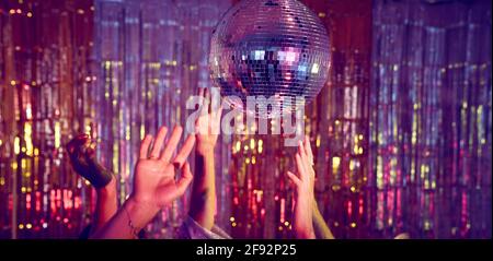 People dancing underneath a glitter ball with just the hands visible.