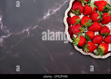 Flat lay of strawberries on a plate against black marble background Stock Photo