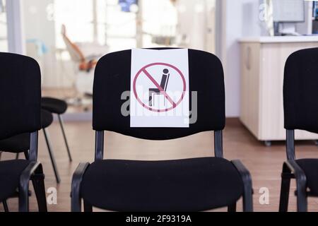 Stomatological empty waiting room during coronavirus outbreak with signs on chairs respecting social distance. Dental clinic with nobody in it, front office with new normal during coronavirus pandemic Stock Photo