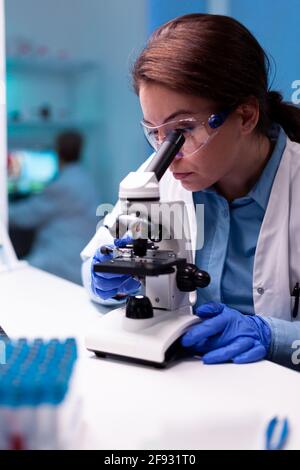 Healthcare scientist looking through microscope in pharmacy lab, healthcare chemical microbiology. Modern laboratory with research equipment for virus study and vaccine science development. Stock Photo