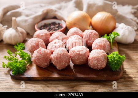 fresh raw meatballs with ingredients for cooking on a wooden board Stock Photo