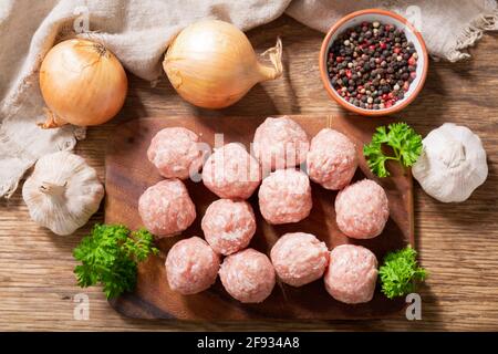fresh raw meatballs with ingredients for cooking on a wooden board, top view Stock Photo