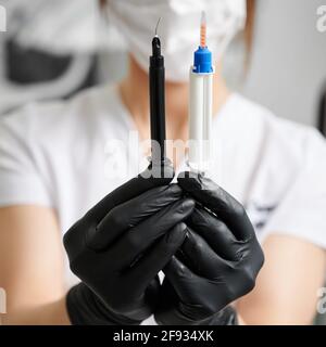 Close up of female stomatologist hands in sterile gloves holding syringe with gel for professional teeth whitening and syringe for gingival protection. Concept of dentistry and dental care. Stock Photo