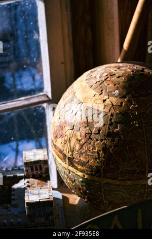 Vertical shot of the globe made from puzzle pieces on a table near the windows Stock Photo
