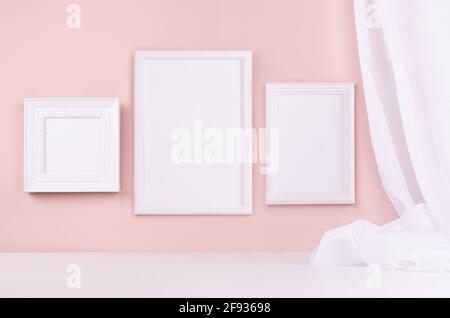 Minimal elegant gallery for display portfolio - three blank  rectangle  photo frames with flow silk curtain hanging on pink wall and white wood table. Stock Photo