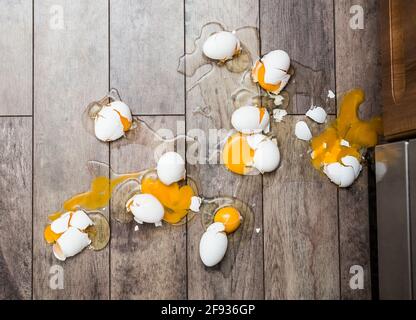 Lot of broken eggs on brown home floor. Misfortune concept. Stock Photo