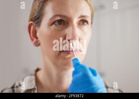 Doctor Carrying Out Rapid Lateral Flow Test For Covid-19 On Mature Woman In Surgery Stock Photo